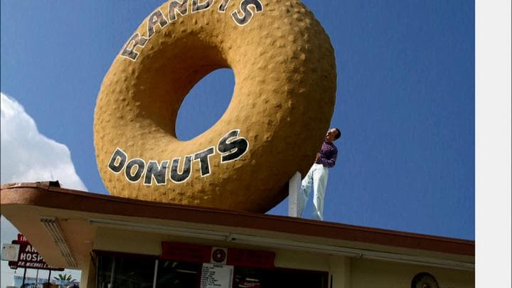 trying to eat his way  through this enormous plaster donut.